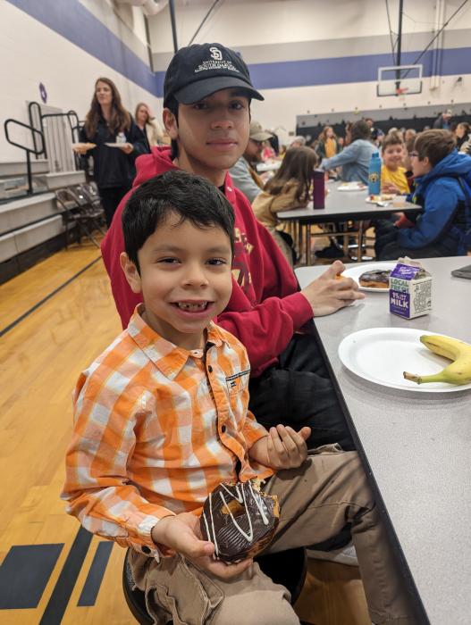 Kindergartener Caleb Romero-Coda enjoyed “Donuts with Grown-ups” in the DV elementary school gym. Romero-Coda was joined by his older brother Nathan, seated next to him, and his mom for the event.